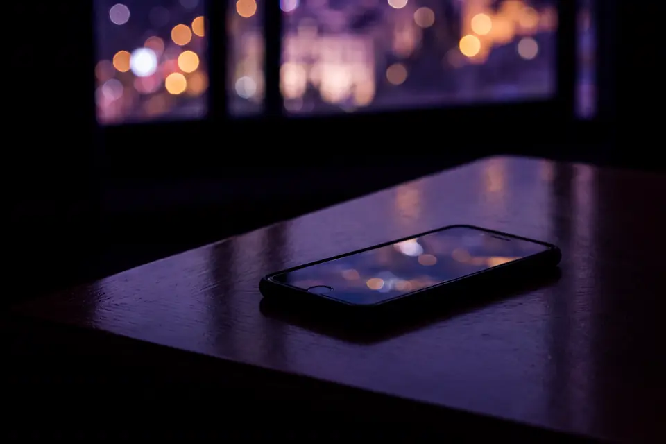 Un móvil sobre una mesa, de noche, junto a la ventana
